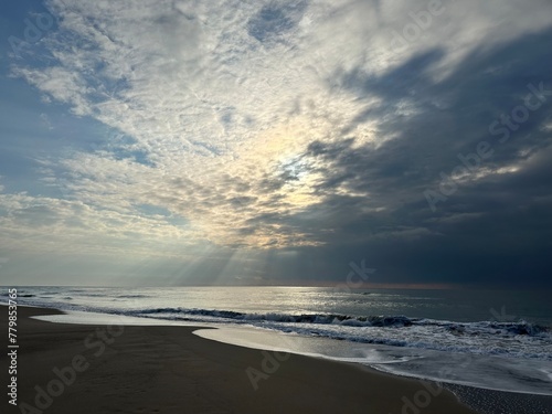 Rising sun shining through clouds on the beach of Castelldefels, Catalonia, Spain, January 2023