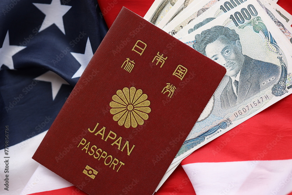 Japan passport with japanese yen money bills on United States flag close up Japan passport with japanese yen money bills on United States flag close up