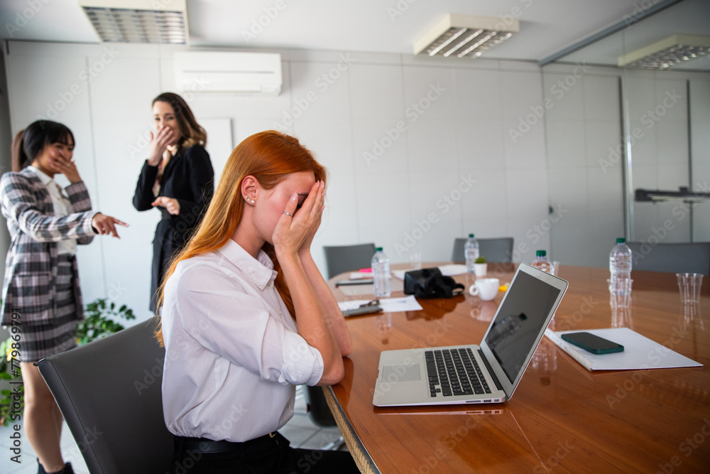 Two business women bully a colleague in the workplace, sad woman feels excluded