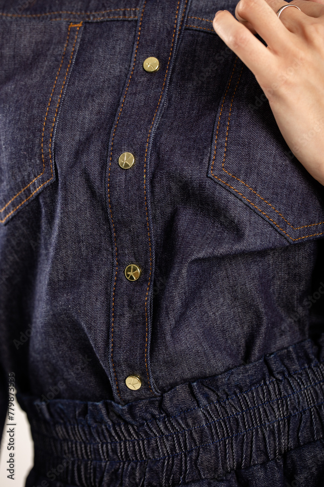 Blue denim shirt with gold buttons on a white background