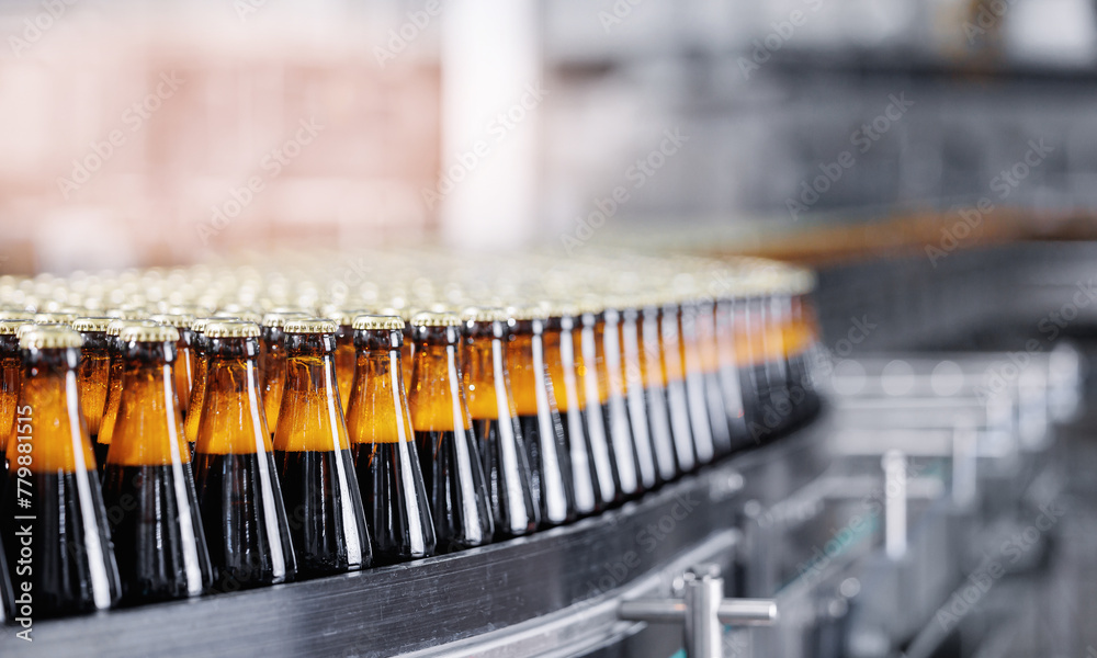 Fototapeta premium Automated modern beer bottling factory line with glasses bottles on conveyor. Banner Brewery industry food manufacturing, sunlight