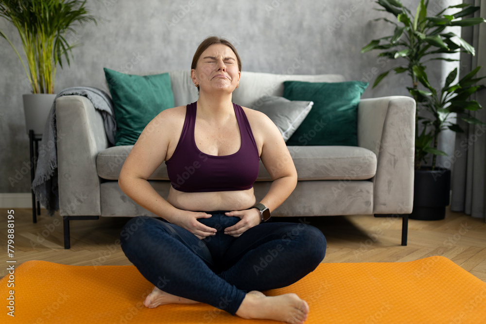 Sad tired fat overweight woman fails to lose weight, can't achieve ideal unattainable figure, loses hope. Young plus size woman in leggings siting on exercise mat and crying