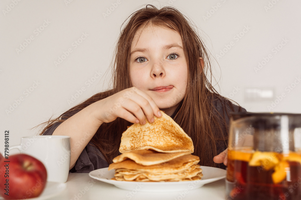 Teenage girl prepares to eat a stack of pancakes while licking her lips. Selected Focus. High quality photo Teenage girl prepares to eat a stack of pancakes while licking her lips. Selected Focus. High quality photo
