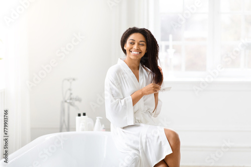 Woman combing hair in bathroom at home