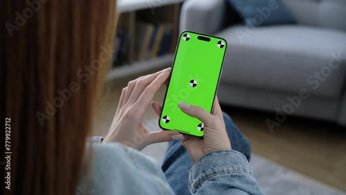 Woman using smartphone vertical green screen. Female holding in hand gadget. Tracking markers. Indoors. Browsing social network, news. Mock-up for tracking. Watching content. Scroll up and tap 4K 