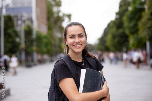 Happy aboriginal female university student holding textbooks 