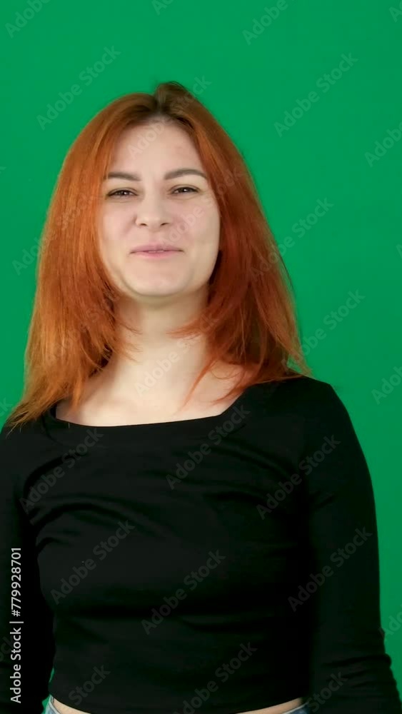 A red-haired girl in black clothes makes dance moves and straightens her hair. green background A red-haired girl in black clothes makes dance moves and straightens her hair. green background