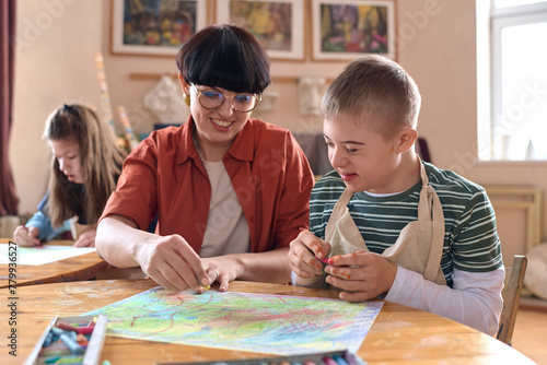 Картината върху платно Portrait of smiling boy with disability enjoying art class in studio with mentor
