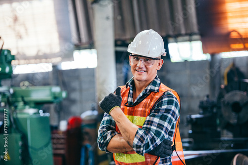 Portrait of male foreman factory wearing hardhat in arms crossed and showing thumb up looking at camera standing at the industry factory. Construction worker career in positive attitude