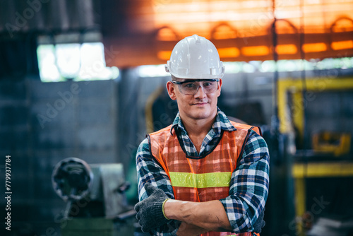 Portrait of male foreman factory wearing hardhat in arms crossed looking at camera standing at the industry factory. Construction worker or builder career in positive attitude. copy space