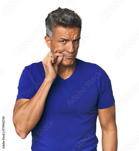 Middle-aged Latino man with fingers on lips keeping a secret.