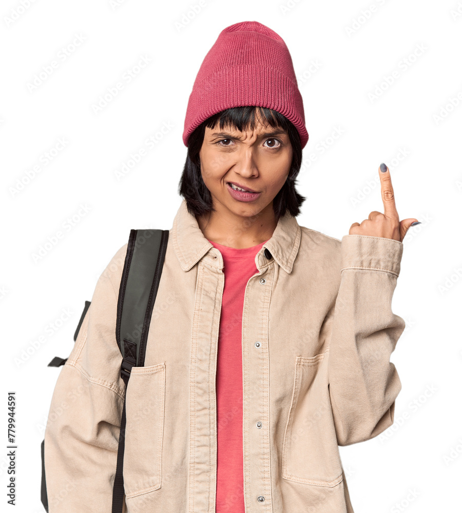 Young student with backpack and beanie in studio showing fist to camera, aggressive facial expression. Young student with backpack and beanie in studio showing fist to camera, aggressive facial expression.