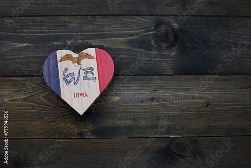 wooden heart with national flag of iowa state on the wooden background.