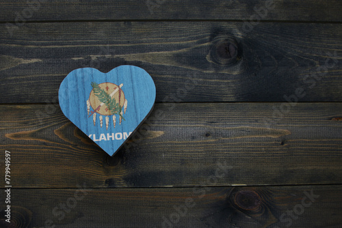 wooden heart with national flag of oklahoma state on the wooden background.