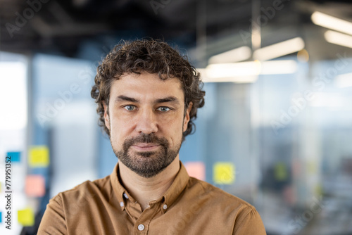 A professional man standing confidently in a well-lit, modern office, conveying concepts of business, success, and corporate lifestyle. © Liubomir