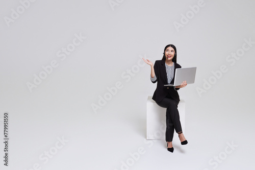 Happy young asian business woman call centre. Welcome female operator put on smalltalk headphone with laptop sitting on chair isolated on white background. photo