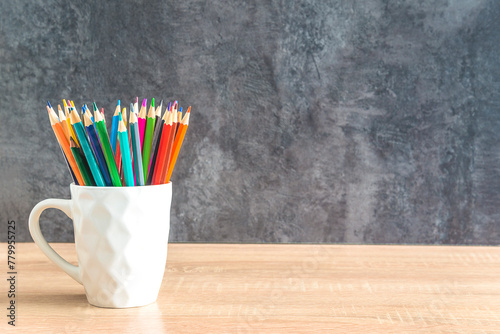 Heap of colorfull pencils on a wooden desk and gray background; copy space for your text