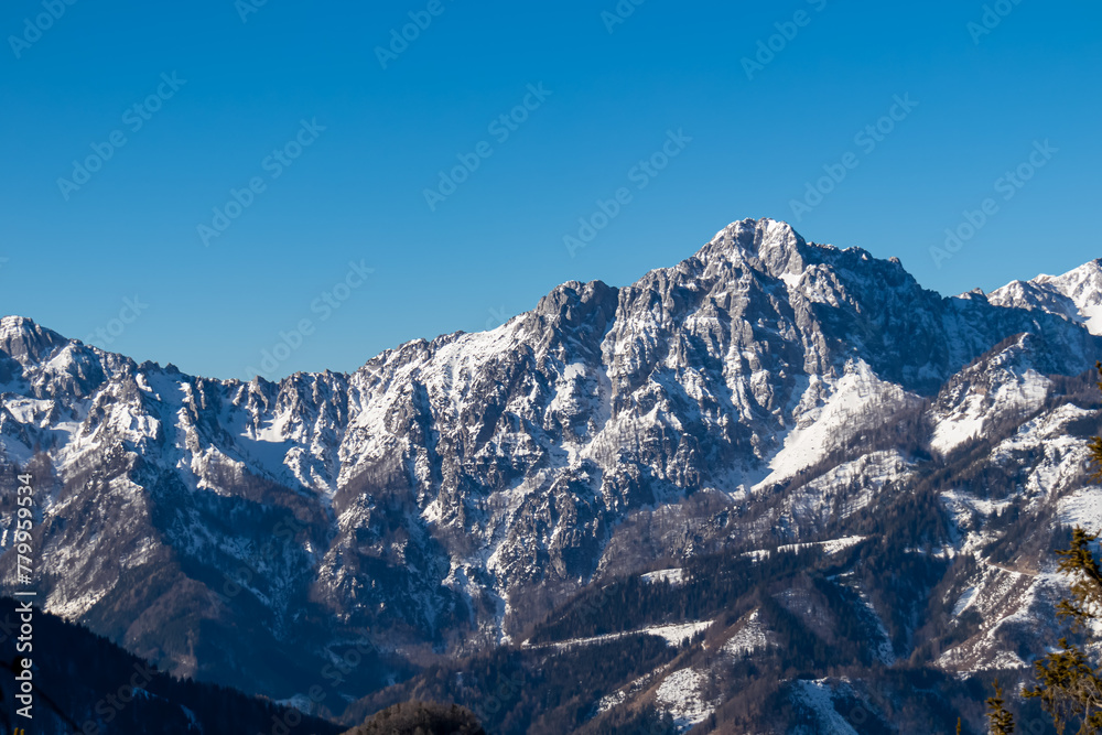 Scenic view on snow capped alpine mountain chains of Karawanks in Carinthia, Austria. Panoramic hiking trail to summit Ferlacher Horn in Austrian Alps in winter. Wanderlust in serene alpine landscape
