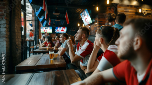 soccer fans sitting in a  pub with beers watching a match on the screens.