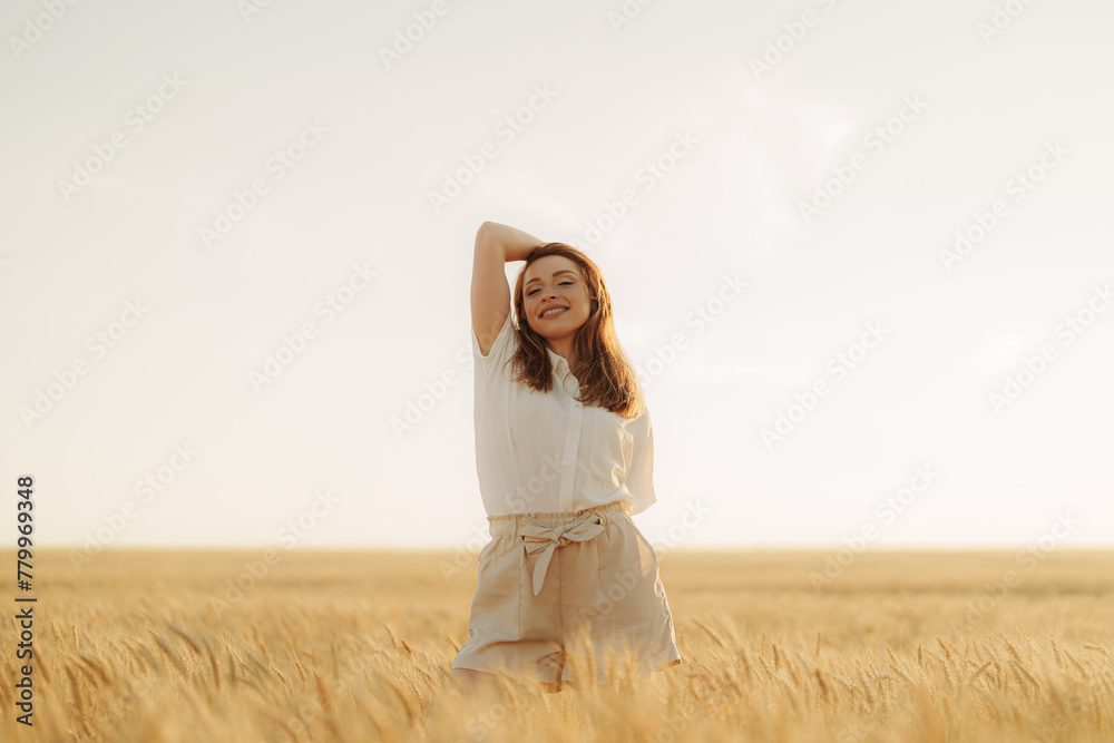Happy young woman in a white shirt standing in a wheat field at sunset, experiencing the beauty of nature. Happy young woman in a white shirt standing in a wheat field at sunset, experiencing the beauty of nature.