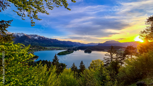 Panoramic sunset view on Lake Faak from Taborhoehe in Carinthia, Austria, Europe. Surrounded by high Austrian Alps mountains. Water surface reflecting soft sunlight. Remote alpine landscape in summer photo