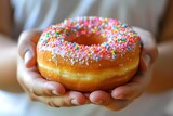 Close-up of a colorful sprinkled donut in hands.
