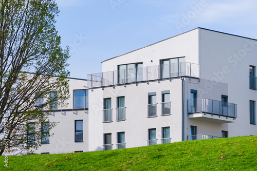 Newly built block of flats in nature. Modern, ecological, generic architecture. New home building and living concept. Housing availability concept. Blue sky background.
