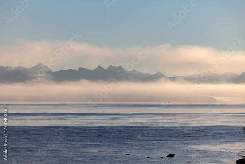 Misty lake framed by mountains, creating a serene natural landscape