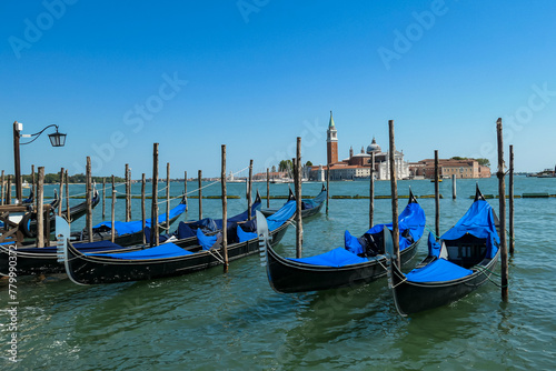 Group of gondolas moored by Saint Mark square in city of Venice  Veneto  Northern Italy  Europe. Scenic view of San Giorgio di Maggiore church in background. Romantic vacation in the Venetian Lagoon