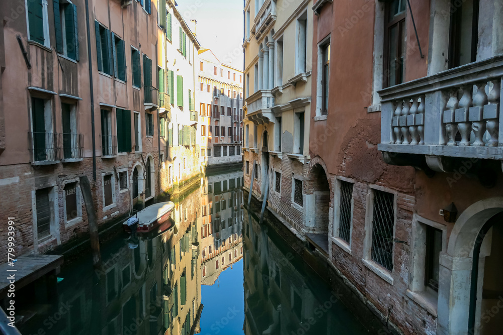 Floating boats with panoramic view of a water channel in city of Venice, Veneto, Italy, Europe. Venetian architectural landmarks and old houses facades along water canal. Urban tourism in summer