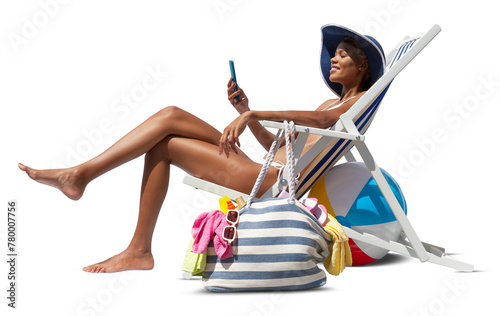 Happy woman at the beach on deck chair, sunbathing, uses the mobile phone, isolated in the white background, concept a summer beach holiday, online shopping, booking travel, and resorts accommodations