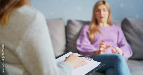 Woman in counseling session with blurred therapist in foreground