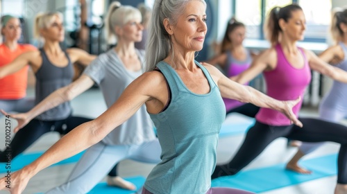 Senior woman performing warrior pose in yoga class. Health and wellness activity concept for design and print. photo