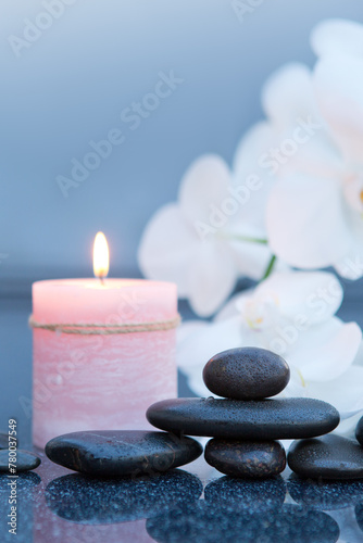 Spa background with white orchid   candle and zen black stones on gray.