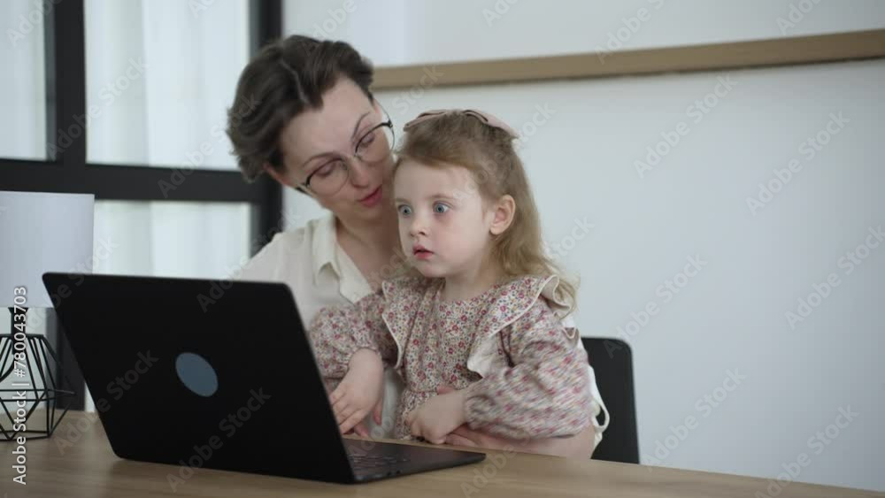 Cheerful woman her little daughter spend free time together at home relaxing on couch with laptop device Cheerful woman her little daughter spend free time together at home relaxing on couch with laptop device
