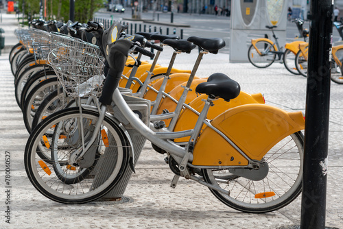 bicycles in the street,Racks for public bicycle services. Yellow bikes are available for rent. City bike rental. Bicycles in the city. Ecological way of transport. Lots of bikes ready to rent