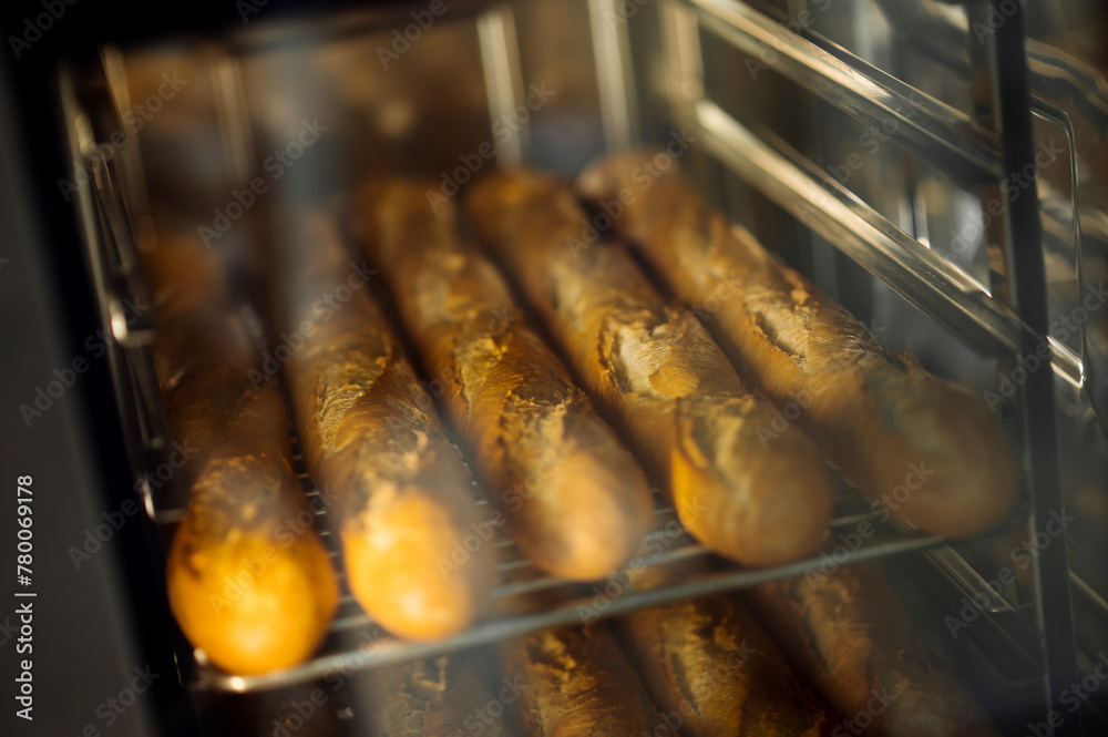Cooking fresh crispy baguettes in oven at bakery Cooking fresh crispy baguettes in oven at bakery