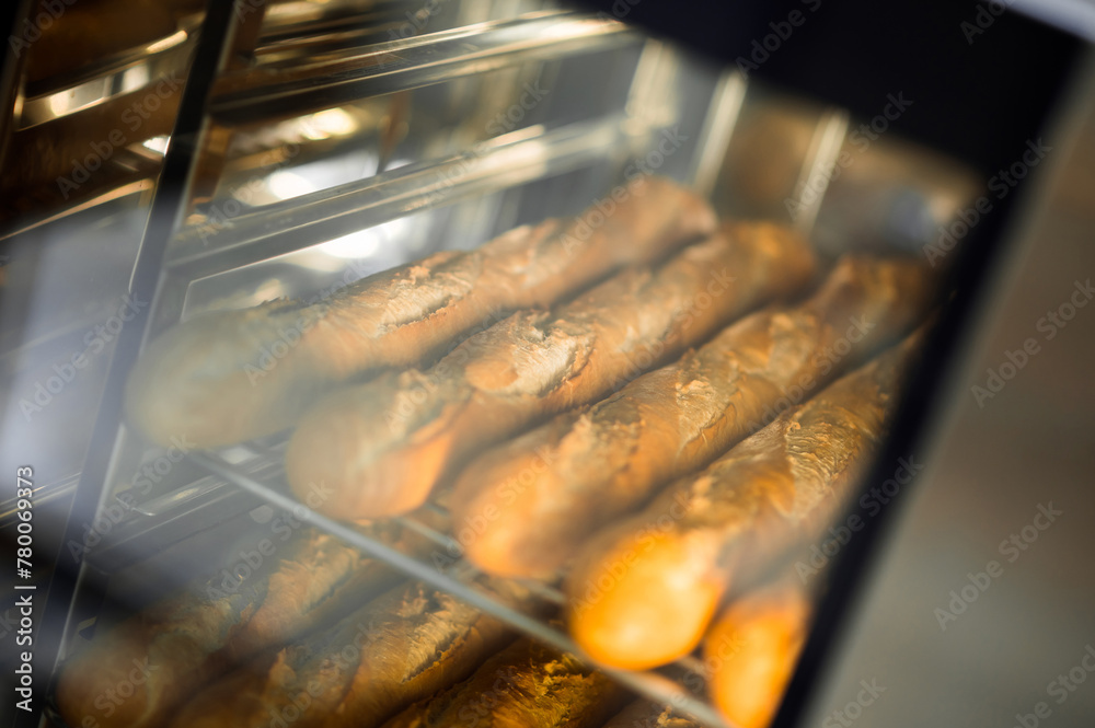 Cooking fresh crispy baguettes in oven at bakery