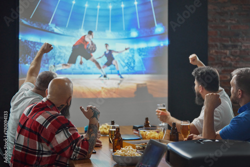 Men, friends sitting at table with beer and snacks, watching online basketball game translation on TV and cheering up favorite team. Concept of sport, championship, game, sport fans, leisure © master1305