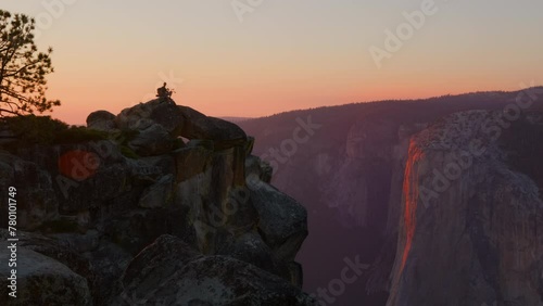 Fantastic view of majestic rock formations of famous Half Dome, lonely man admiring the beauty of impressive ancient rocks on the peak under orange skies. High quality 4k footage photo