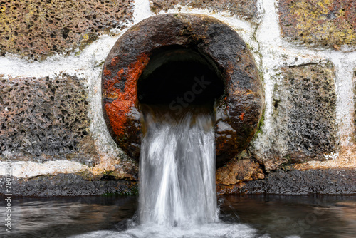 Água a cair de um bucal de pedra.  photo