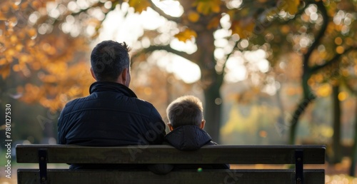 Father and son sitting on a park bench, Father's Day concept.