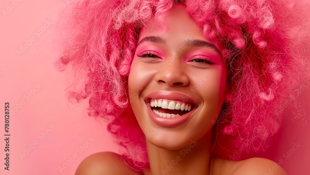 A happy woman in pink hair and smiling on a pink background with space for text.