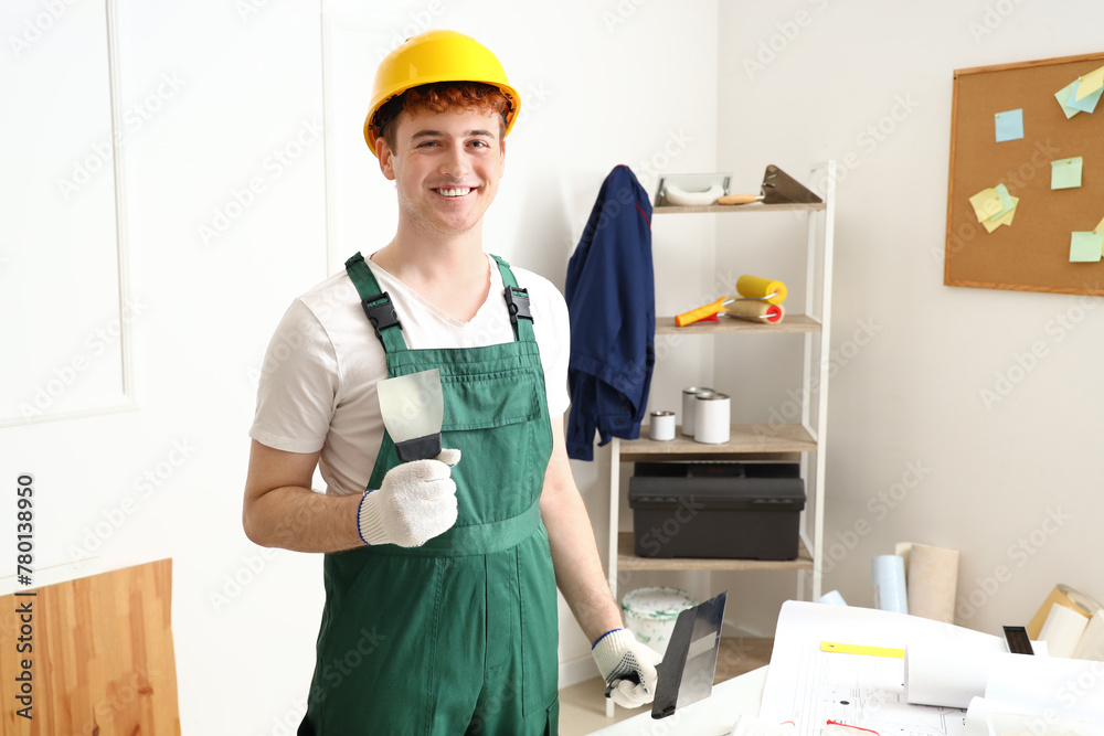 Male decorator with putty knife working in room Male decorator with putty knife working in room