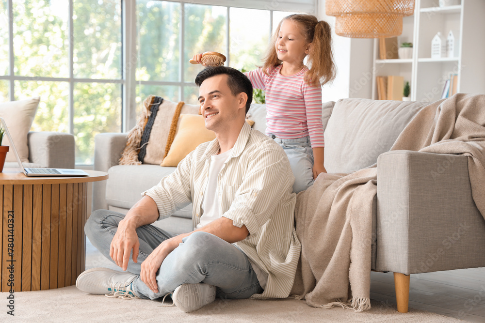 Cute little girl brushing her dad's hair at home