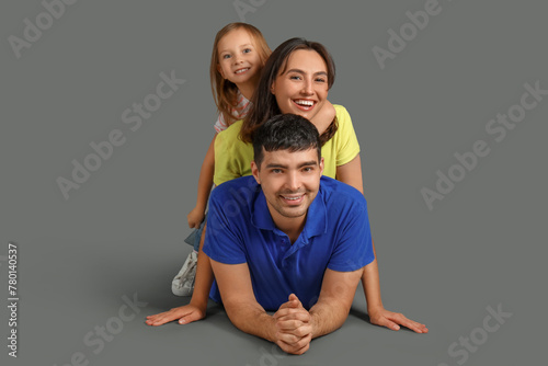 Happy family dreaming about their new house lying on grey background © Pixel-Shot