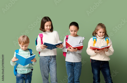 Little schoolchildren with books on green background photo