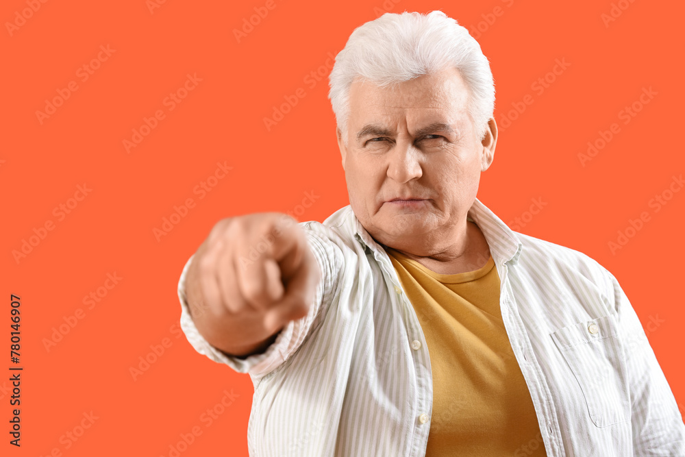 Mature man pointing at viewer on orange background, closeup. Accusation concept Mature man pointing at viewer on orange background, closeup. Accusation concept