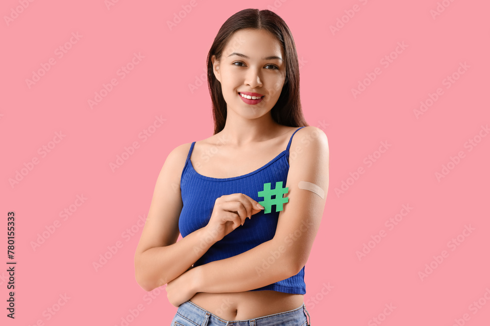 Beautiful young woman with applied medical patch holding hashtag sign on pink background - obrazy, fototapety, plakaty 