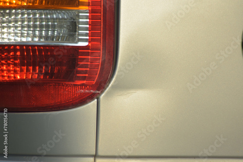 Close up of the rear turn signal dent of a silver-bronze car from accident. Damage car accident, copy space.